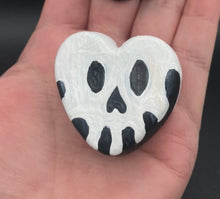Load image into Gallery viewer, Perfect cute and spooky Halloween magnet art to add to your fridge, locker, cubicle or toolbox.  This hand-crafted black heart-shaped magnet features a white skull figurine  with distinctive black eyes.   Measurements: H 1 1/2” x W 1 5/8” x D 1/2”
