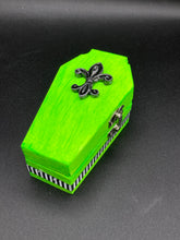 Load image into Gallery viewer, This Lime Green BeetleJuice-inspired Wood Coffin Ring Box is perfect for storing special items. The eye-catching black-silver fleur de lis embellishment and the black and white stripped ribbon gives the box a unique and spooky, yet cute and misfit look. Its all-black interior elevates the aesthetic of this stylish box.
