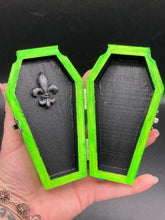 Load image into Gallery viewer, This Lime Green BeetleJuice-inspired Wood Coffin Ring Box is perfect for storing special items. The eye-catching black-silver fleur de lis embellishment and the black and white stripped ribbon gives the box a unique and spooky, yet cute and misfit look. Its all-black interior elevates the aesthetic of this stylish box.
