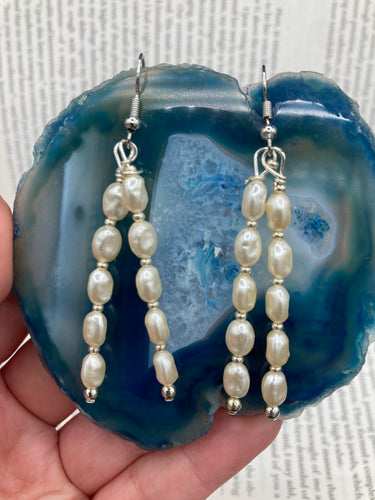 Two long strands of simulated white baroque pearls and silver glass beads come together to create this exquisite accessory.  Measurements: 2” in length 