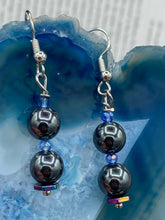 Load image into Gallery viewer, These chic earrings, crafted with two Hematite beads and blue glass beads, provide a stylish accent.  Measurements: 1 1/4” in length
