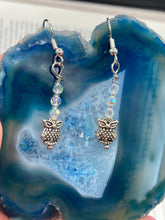 Load image into Gallery viewer, These sleek earrings feature tiny glass beads with a shimmery iridescent and silver finish, along with silver-plated owls for a stylish touch.  Measurements: 1 1/4” in length
