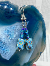 Load image into Gallery viewer, Glass beaded earrings take center stage in this design, with light blue glass beads as the primary color. These beads contain varying shades of blue, purple, and a hint of gold to add interest and texture to the style. As a show-stopping accessory, this piece of jewelry is a must-have for any collection.  Measurements: 1 3/8” in length
