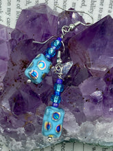 Load image into Gallery viewer, Glass beaded earrings take center stage in this design, with light blue glass beads as the primary color. These beads contain varying shades of blue, purple, and a hint of gold to add interest and texture to the style. As a show-stopping accessory, this piece of jewelry is a must-have for any collection.  Measurements: 1 3/8” in length
