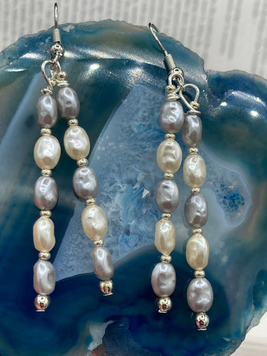 This piece is crafted with two strands of faux baroque pearls in white and gray, as well as silver glass beads. Measurements: 2” in length 