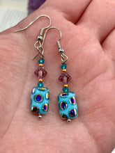 Load image into Gallery viewer, These whimsical earrings feature an eye-catching blend of bright blue glass beads, which feature a blend of blues, purples, and hints of gold. They are further complemented by varying sizes and shapes to create a unique texture and style. This vibrant jewelry is a must-have for any collection.  Measurements: 1 ” in length
