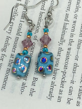 Load image into Gallery viewer, These whimsical earrings feature an eye-catching blend of bright blue glass beads, which feature a blend of blues, purples, and hints of gold. They are further complemented by varying sizes and shapes to create a unique texture and style. This vibrant jewelry is a must-have for any collection.  Measurements: 1 ” in length
