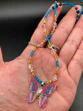 Load image into Gallery viewer, This delicate butterfly pendant is crafted from a basil leaf and adorned with accents of pink, gold and blue. A shining glass beaded necklace crafted from beads of varying shades of pink, gold, and blue, creates a beautiful accompaniment to the butterfly wings. Wear this ravishing necklace and butterfly jewelry pendant to embody the spirit of warm Spring and Summer days. 16 1/4” in length adjustable up to 18&quot;
