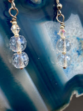 Load image into Gallery viewer, These earrings feature two shimmery iridescent glass beads with a single silver glass bead.  Measurements: 1 1/2” in length
