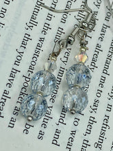 Load image into Gallery viewer, These earrings feature two shimmery iridescent glass beads with a single silver glass bead.  Measurements: 1 1/2” in length 
