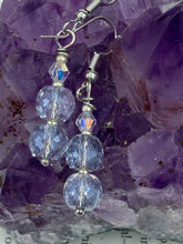 Load image into Gallery viewer, These earrings feature two shimmery iridescent glass beads with a single silver glass bead.  Measurements: 1 1/2” in length
