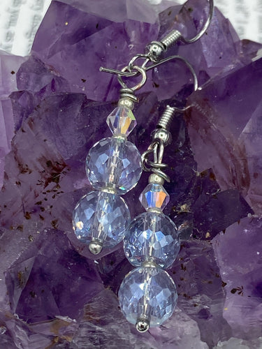 These earrings feature two shimmery iridescent glass beads with a single silver glass bead.  Measurements: 1 1/2” in length