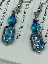Load image into Gallery viewer, These whimsical earrings feature an eye-catching blend of bright blue glass beads, which feature a blend of blues, purples, and hints of gold. They are further complemented by varying sizes and shapes to create a unique texture and style. This vibrant jewelry is a must-have for any collection.  Measurements: 1 ” in length
