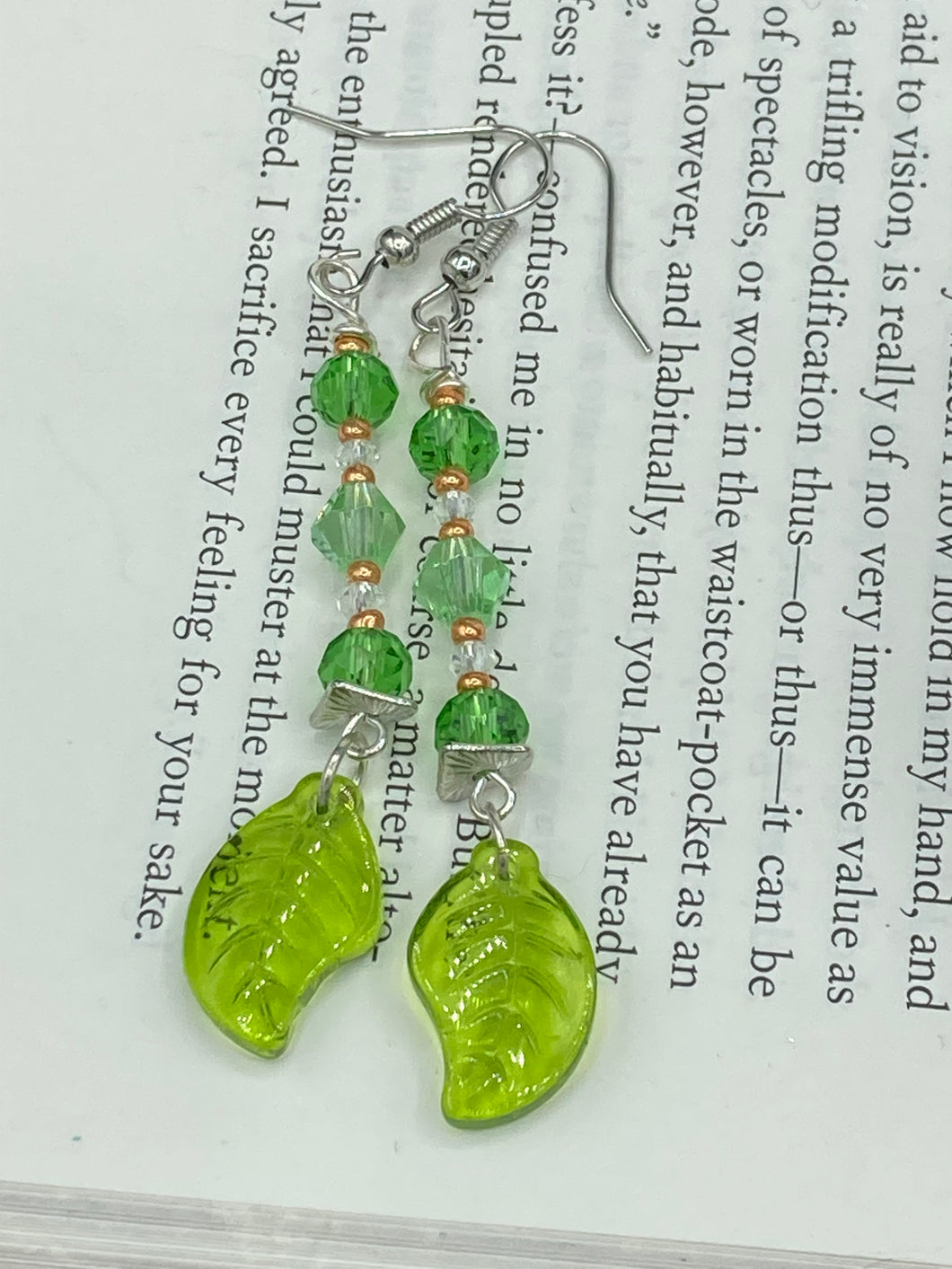 Long strand of glittering light green and gold glass beads, as well as a leaf-shaped glass charm at the bottom, combine to create a highly dynamic effect. These versatile earrings, perfect for a whimsical fairy princess, good witch, or nature-loving hippie look, draw on nature-inspired designs, providing the ideal finishing touch to any ensemble.  Measurements: 2 1/4” in length