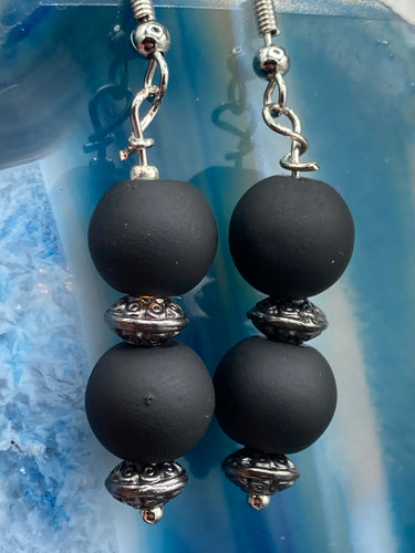 These flat matte black round glass bead earrings with silver plated floral beads offer a versatile look perfect for cocktail chic attire, a wedding necklace, and minimalist style. Measurements: 1 1/4” in length