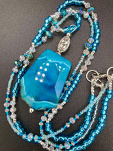 Load image into Gallery viewer, This Vibrant Sea Blue Agate Natural Stone Pendant Choker Style Beaded Necklace includes two strands of glass beads in shades of blues, silver and clear to lend shimmer and color to this large stone pendant. The shorter strand consists of very light blue small glass beads, while the longer strand is primarily a light baby blue. A set of dainty matching earrings completes the look. This beautiful gemstone necklace is the perfect accessory to bring the beach with you in the coming months.
