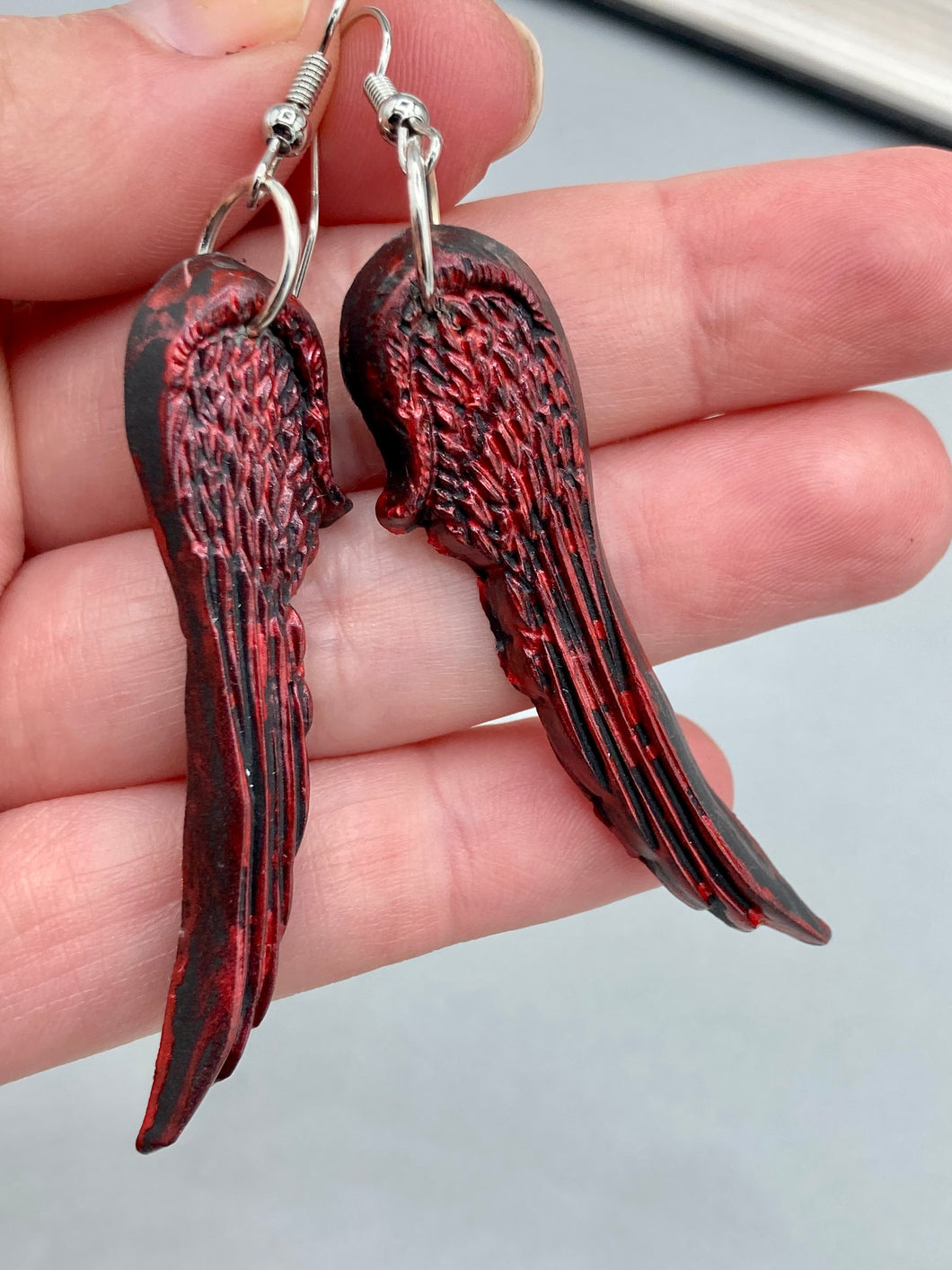 Red angel wings earrings made of polymer clay.  These earrings are designed to face forward when worn instead of the front wings showing on the side.
