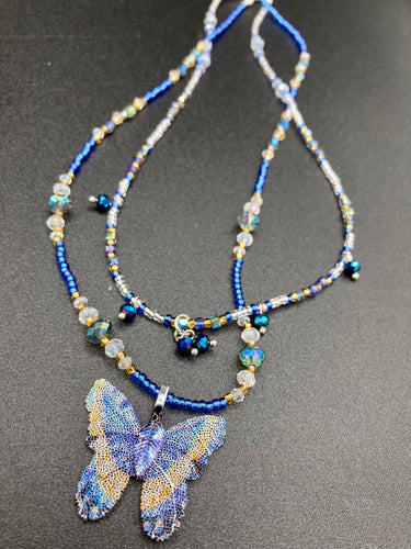 This Sterling Silver Dark Blue, Silver and Gold Butterfly Pendant is handcrafted from a basil leaf, and is meticulously painted in brilliant blues and silver. A range of multi-colored glass beads from deep blue to pale silver and gold tones combine to create a stunning lapis stone-like effect. This nature-inspired jewelry piece is perfect for adding a touch of summery style to any look.  Measurements:   Necklace is 15 1/2” adjustable up to 18