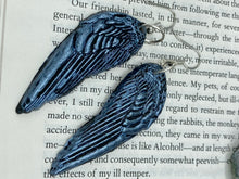 Load image into Gallery viewer, Shimmery silver color angel wings earrings made of polymer clay.  These earrings are designed to face forward when worn instead of the front wings showing on the side.
