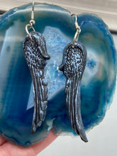 Load image into Gallery viewer, Shimmery silver color angel wings earrings made of polymer clay.  These earrings are designed to face forward when worn instead of the front wings showing on the side.
