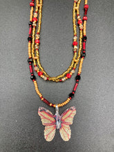 Load image into Gallery viewer, This intricately crafted pendant features a Basil leaf molded in Sterling Silver and adorned with stunningly vivid red, gold, and black glass beaded necklace. Its eye-catching butterfly design adds a bold, yet whimsical touch, making it an ideal choice for a summer look. Necklace is 15 1/2” in length adjustable to 18&quot;
