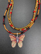 Load image into Gallery viewer, This intricately crafted pendant features a Basil leaf molded in Sterling Silver and adorned with stunningly vivid red, gold, and black glass beaded necklace. Its eye-catching butterfly design adds a bold, yet whimsical touch, making it an ideal choice for a summer look. Necklace is 15 1/2” in length adjustable to 18&quot;
