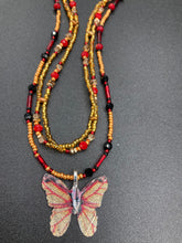Load image into Gallery viewer, This intricately crafted pendant features a Basil leaf molded in Sterling Silver and adorned with stunningly vivid red, gold, and black glass beaded necklace. Its eye-catching butterfly design adds a bold, yet whimsical touch, making it an ideal choice for a summer look. Necklace is 15 1/2” in length adjustable to 18&quot;
