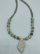 Load image into Gallery viewer, This exquisite necklace showcases earthy tones of mossy green ceramic beads, complemented by a gray toned howlite stone chip pendant. To add a sparkle, I interspersed gold-tone glass beads between each ceramic one. Two delicate strands feature small glass beads with hues of blue, gold, and purple. These are bridged by flower-shaped gold plated beads, which then unite with the round ceramic beads. This alluring earth-tone combination makes a stunning accessory. Necklace is 17” 

