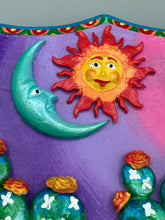 Load image into Gallery viewer, This handcrafted polymer clay wall art features a wood frame painted in a gradient from light pink to dark purple, creating a stunning sunset look. With two bright green skull cactus plant and bright yellow orange blooming flowers. Featuring a vivid sun and crescent moon with a backdrop of dark blue clouds, this frame is sure to make an impression. A bight teal and yellow hue frame to make a bold contrast with the warm background hue. This piece is sure to make a statement.
