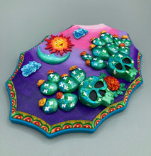 Load image into Gallery viewer, This handcrafted polymer clay wall art features a wood frame painted in a gradient from light pink to dark purple, creating a stunning sunset look. With two bright green skull cactus plant and bright yellow orange blooming flowers. Featuring a vivid sun and crescent moon with a backdrop of dark blue clouds, this frame is sure to make an impression. A bight teal and yellow hue frame to make a bold contrast with the warm background hue. This piece is sure to make a statement.
