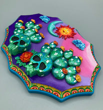 Load image into Gallery viewer, This handcrafted polymer clay wall art features a wood frame painted in a gradient from light pink to dark purple, creating a stunning sunset look. With two bright green skull cactus plant and bright yellow orange blooming flowers. Featuring a vivid sun and crescent moon with a backdrop of dark blue clouds, this frame is sure to make an impression. A bight teal and yellow hue frame to make a bold contrast with the warm background hue. This piece is sure to make a statement.

