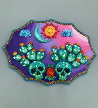 Load image into Gallery viewer, This handcrafted polymer clay wall art features a wood frame painted in a gradient from light pink to dark purple, creating a stunning sunset look. With two bright green skull cactus plant and bright yellow orange blooming flowers. Featuring a vivid sun and crescent moon with a backdrop of dark blue clouds, this frame is sure to make an impression. A bight teal and yellow hue frame to make a bold contrast with the warm background hue. This piece is sure to make a statement.
