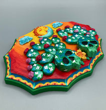 Load image into Gallery viewer, This handcrafted polymer clay wall art features a wood frame painted in a gradient from light yellow to dark red, creating a stunning sunset look. With two bright green skull cactus plant and bright dark red blooming flowers. Featuring a vivid sun and crescent moon with a backdrop of light blue clouds, this frame is sure to make an impression. A bight green hue frame to make a bold contrast with the warm background hue. This piece is sure to make a statement.
