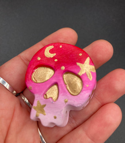 Inspired by nature, this skull statuette is full of vibrant colors and intricate details. The ombre colors from red, to light pink was inspired by the summer sky at sundown that I see all too often. I really wanted to capture those beautiful colors and added metallic gold moon and stars silhouettes to tie it all together. 