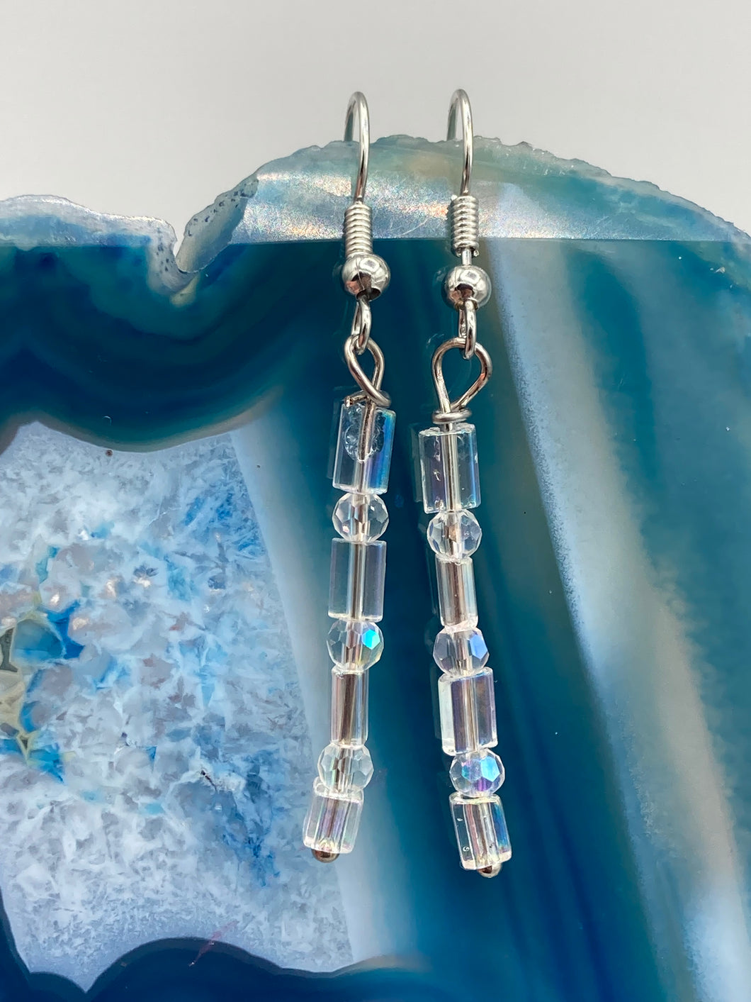 This pair of earrings features two strands of sparkling glass beads, in both rectangular and round shapes, with an iridescent sheen.  Measurements: 1 3/16” in length   
