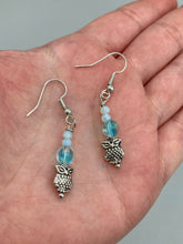 Load image into Gallery viewer, Beautiful delicate glass beaded earrings featuring silver-plated night owl charms in an enchanting pale blue hue.  Measurements: 1 1/4” in length
