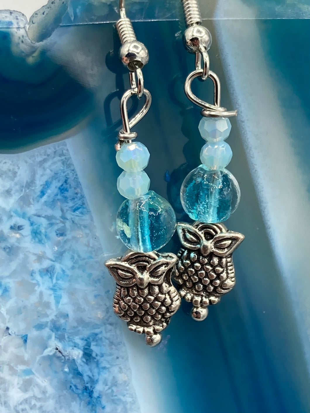 Beautiful delicate glass beaded earrings featuring silver-plated night owl charms in an enchanting pale blue hue.  Measurements: 1 1/4” in length