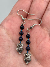 Load image into Gallery viewer, Showcasing shimmery purple goldstone beads, these classy silver-plated owl charm earrings make a statement.  Measurements: 1 3/16” in length
