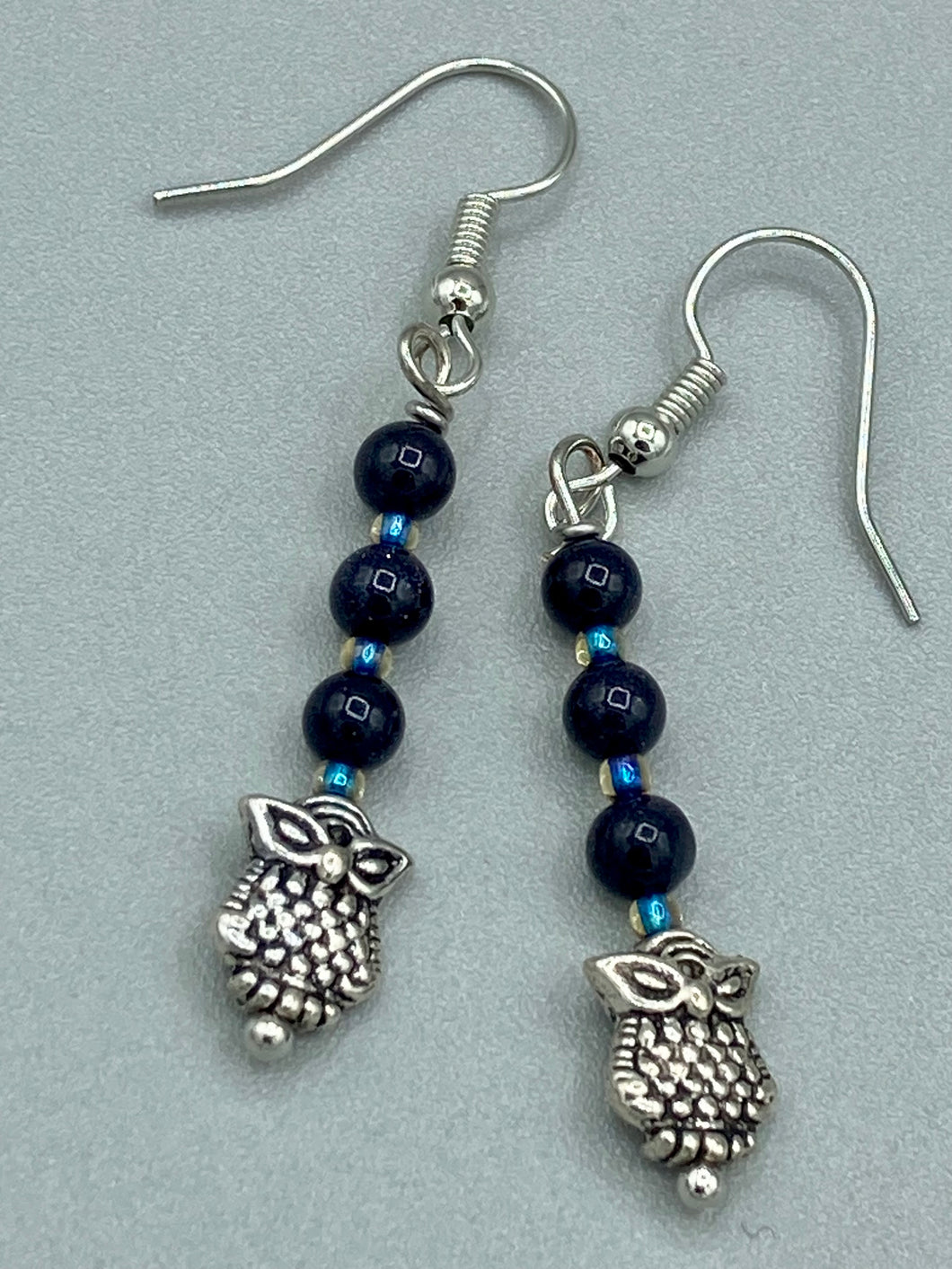 Showcasing shimmery purple goldstone beads, these classy silver-plated owl charm earrings make a statement.  Measurements: 1 3/16” in length
