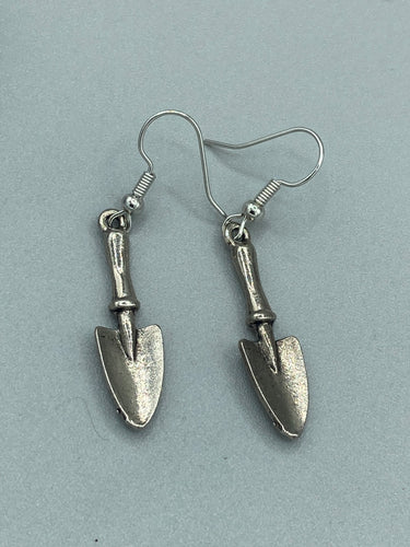 Gift the gardener in your life with these Garden Trowel Charm Earrings, a perfect piece of jewelry for garden lovers. The earrings feature a delicately crafted Trowel Tool Charm and are sure to make a statement. A memorable gift for any gardener!  Measurements: 1 1/2” in length