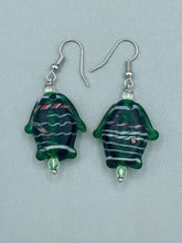 Load image into Gallery viewer, These nature-inspired glass fish earrings are the perfect addition to your boho look. Featuring a delightful dark green hue, the large puffy fish will bring a hippie vibe to your style. Measurements: 1 1/2” in length
