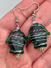 Load image into Gallery viewer, These nature-inspired glass fish earrings are the perfect addition to your boho look. Featuring a delightful dark green hue, the large puffy fish will bring a hippie vibe to your style. Measurements: 1 1/2” in length
