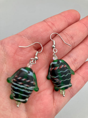 These nature-inspired glass fish earrings are the perfect addition to your boho look. Featuring a delightful dark green hue, the large puffy fish will bring a hippie vibe to your style. Measurements: 1 1/2” in length