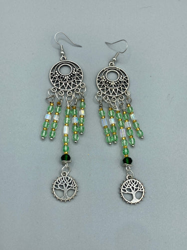 Be mesmerized by these large cascade style earrings, featuring five delicate strands of light green, iridescent and gold-tone beads with a tree of life charm for an eye-catching effect. Perfect for whimsical, nature-inspired looks, these earrings will liven up any outfit.  Measurements: 3 3/4” in length 