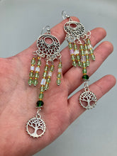 Load image into Gallery viewer, Be mesmerized by these large cascade style earrings, featuring five delicate strands of light green, iridescent and gold-tone beads with a tree of life charm for an eye-catching effect. Perfect for whimsical, nature-inspired looks, these earrings will liven up any outfit.  Measurements: 3 3/4” in length 
