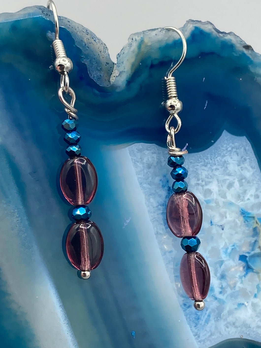 These dainty earrings feature a combination of light purple and dark blue glass beading for a sophisticated, versatile look. Perfect for a chic aesthetic, these earrings can easily complement any outfit.  Measurements: 1 3/8” in length
