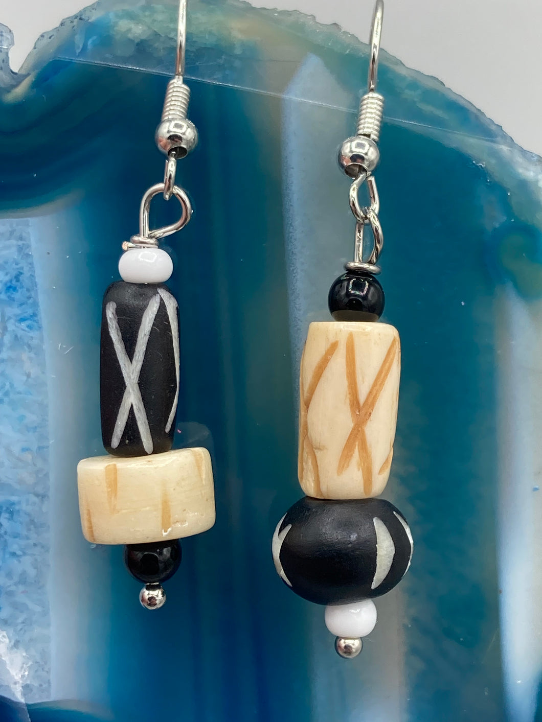 This set of earrings is crafted from a mix of bone and wood carved beads, giving it an eye-catching, one-of-a-kind look. It's versatile enough to dress up or down, making it a great choice for any occasion.  Measurements: 1 1/2 ” in length  