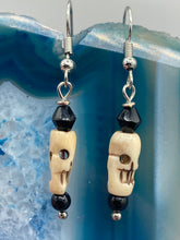 Load image into Gallery viewer, This set of mini bone skull earrings with black glass beads is an ideal addition to any gothic, emo, or witchy-inspired look. The unique day-of-the-dead aesthetic of these earrings will add a special touch to any outfit — dress them up or dress them down!   Measurements: 1 1/4 ” in length  

