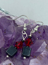 Load image into Gallery viewer, This eye-catching piece features two unconventional components: a large square-shaped black obsidian bead and a large, dark red glass bead. With the beautiful interplay of colors and shapes, these earrings are truly unique, yet at the same time, versatile enough to be paired with a range of styles. Measurements: 1” in length 
