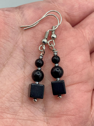 These earrings are crafted with large square-shaped black obsidian beads and small round-shaped black obsidian beads, paired with light gray glass beads. This combination provides an eye-catching, yet versatile look. Measurements: 1” in length